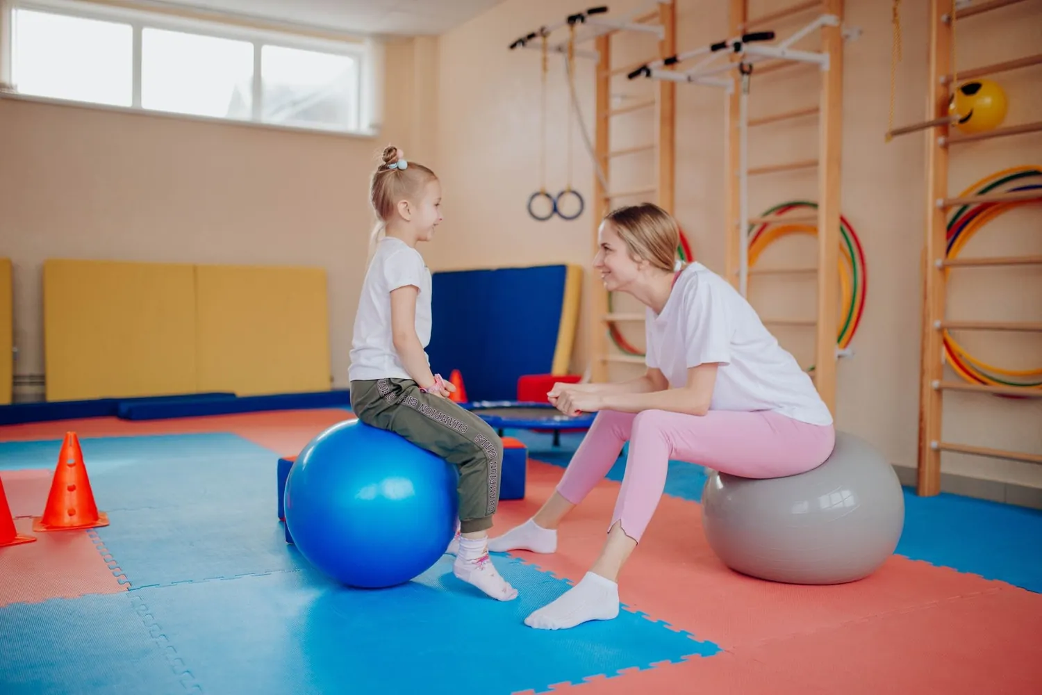 Criança em atividade de fisioterapia com bola em sala de terapia